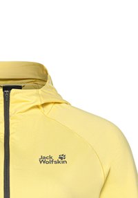 Giacca leggera gialla con chiusura a zip, cappuccio e logo grigio sul petto. Presenta una texture morbida e un design snello.