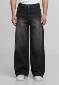 Jeans negros de pierna ancha con un acabado desgastado, que cuentan con un cierre de botón, cinco bolsillos y un parche con el logo en el bolsillo delantero izquierdo.