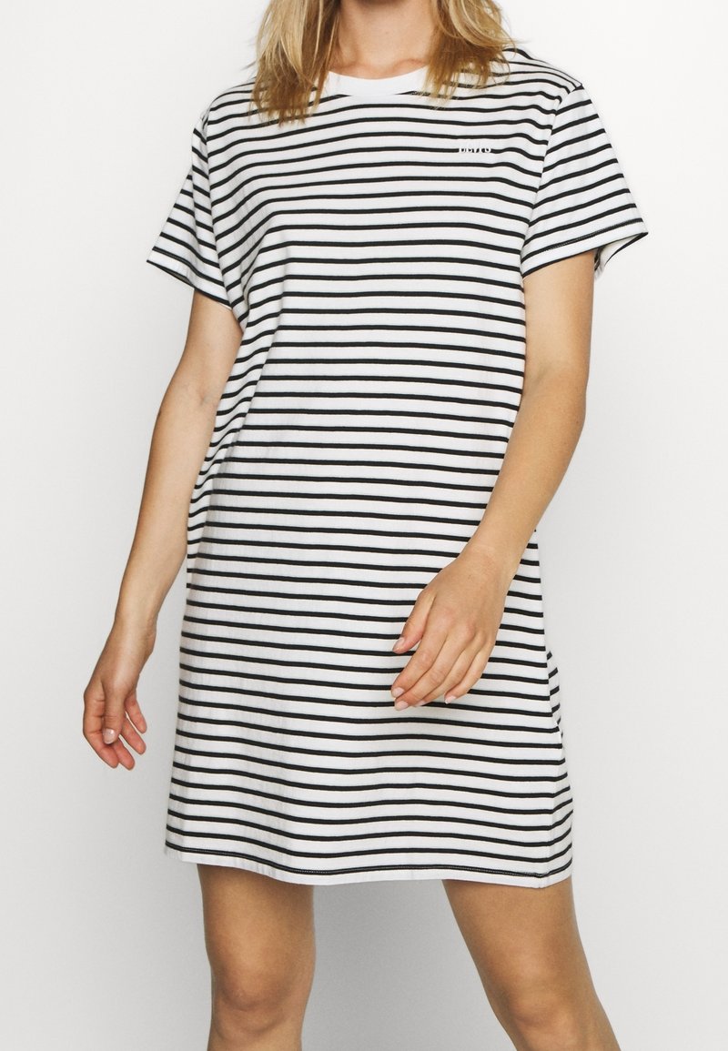 Robe rayée avec des rayures horizontales noires et blanches, tissu doux, manches courtes, coupe décontractée et petit logo sur la poitrine.