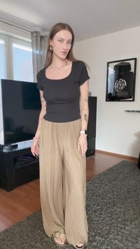 Mustmust, lühikeste varrukatega must topp, millele on paari pandud beežid kortsunud laiad püksid. Riietusel on sile tekstuur ja pehme, mugav istuvus.