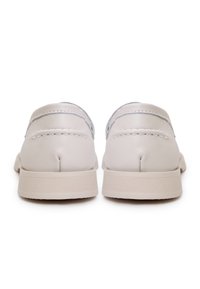 Paire de mocassins en cuir beige clair vue de dos, montrant des détails cousus et des semelles en caoutchouc côtelées sur fond blanc.