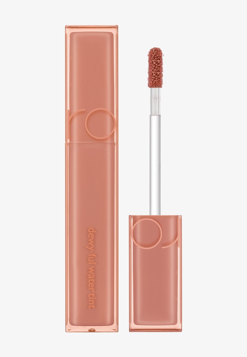 Teinture d'eau rosée dans un tube transparent pêche. Doté d'un applicateur doux et duveteux avec un embout arrondi. La couleur de base est pêche clair avec du texte en relief.