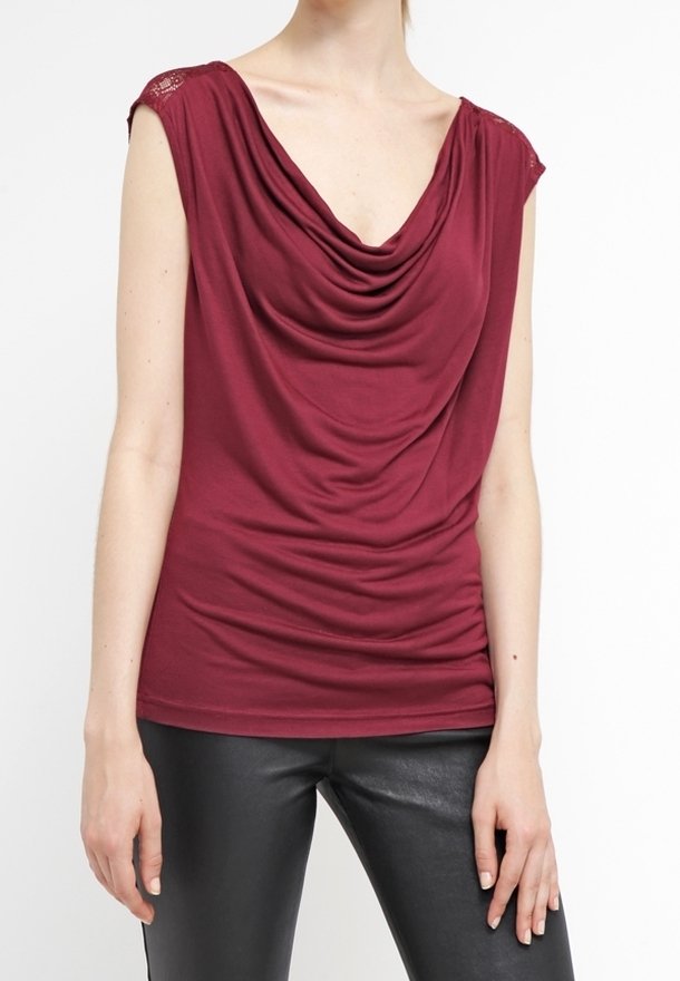 Top drape burdeos con escote en V y mangas de cap sleeve; cuenta con textura fruncida y acentos de encaje en los hombros; diseño en capas para mayor caída.
