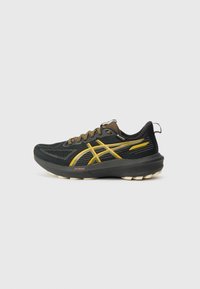 Chaussure de course en maille noire avec des accents jaunes, design texturé et lacets marron. Présente une épaisse semelle noire avec un amorti visible.