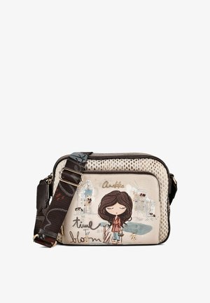 Beige Umhängetasche mit verstellbarem dunkelblumigem Riemen, mit Cartoon-Mädchen-Illustration und Text "time to bloom" auf der Vordertasche.