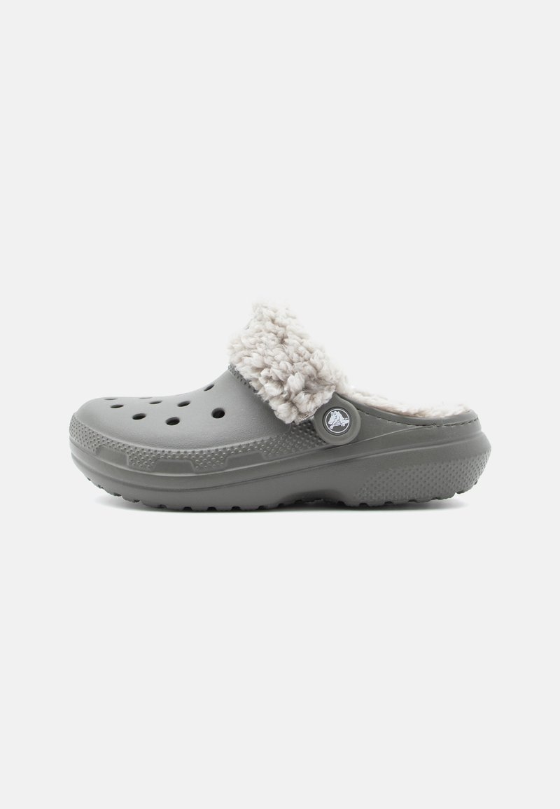 Sabot gris avec une doublure blanche en fourrure, doté de trous de ventilation, d'un bouton logo circulaire et d'une semelle texturée pour une meilleure adhérence.