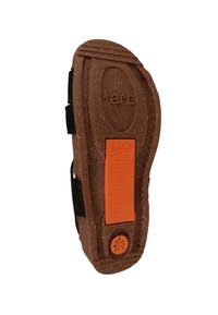 Brun struktureret sål med dybe riller, der har en markant orange etiket og logo. Fremstillet af genbrugsmaterialer, hvilket understreger miljøvenlighed.