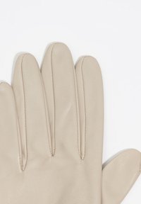 Guante de cuero beige con tres dedos articulados. Textura suave y costuras limpias. Las costuras pronunciadas entre los dedos mejoran la flexibilidad.