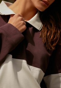 Bordeaux-rot und weißes Polo-Shirt mit einem weißen Kragen, aus strukturiertem Stoff und mit einem kontrastierenden Farbkombinationsdesign.