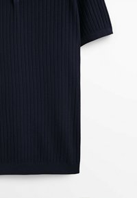 Pull en maille bleu marine à manches courtes avec motif côtelé vertical, montrant partiellement le devant et la manche droite sur fond blanc.