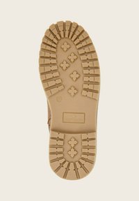 Semelle d'une botte marron clair avec des motifs de crampons profonds, comprenant des croix et des lignes, marquée de la taille 33 et du logo de la marque Tom Tailor.
