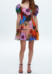 Robe courte colorée avec un corsage ajusté, des manches bouffantes et une jupe évasée. Présente un motif floral en teintes vives sur un tissu texturé.