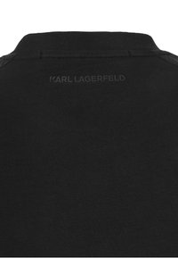 Svart t-shirt med rund halsringning. Baksidan visar en diskret, präglad "KARL LAGERFELD" logotyp. Mjuk, texturerad tyger med en klassisk passform.