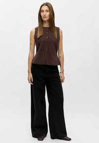 Haut sans manches marron avec un buste ajusté, doté d'un devant boutonné et d'un ourlet peplum, associé à un pantalon noir taille haute et à jambes larges.