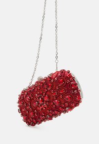 Pochette rouge ornée avec une texture en perles, une chaîne en argent et un fermoir métallique. Des motifs de gemmes complexes décorent la surface.