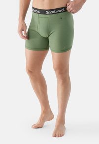 Olivgrüne Boxer-Briefs mit einem schwarzen Bund, auf dem "Smartwool" steht. Sie verfügen über einen Eingriff, eine glatte Textur und subtile Markenakzente.