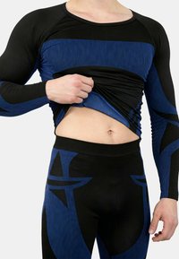 Long-sleeve athletic top in black and blue with ribbed texture; paired with matching fitted pants featuring bold blue graphic designs.