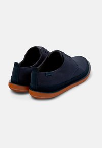 Navy canvas shoes with suede accents, round toe, and brown rubber sole. Features lace-up closure and logo on heel.