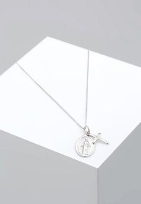 Sidabrinė vėrinio grandinėlė su apvaliu pakabuku, kuriame yra išraiškingas figūros atvaizdas ir kryžiaus pakabukas, subtiliai uždėta ant plonos grandinėlės paprastame fone.