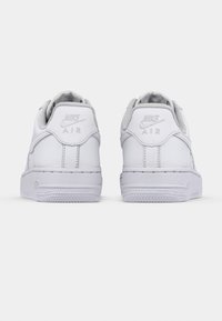 Pair of white Nike Air sneakers viewed from the back on a plain light background, showing logos on the heel tabs.