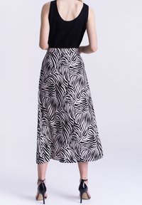 Zwart mouwloos topje, gecombineerd met een knie-lange rok met een zwart-wit zebrapatroon, gladde textuur en een uitlopende ontwerp.