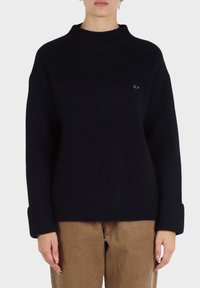 Maglione blu navy a costine con collo alto, vestibilità oversize e un piccolo logo ricamato sul lato sinistro. Tessuto testurizzato con maniche lunghe.