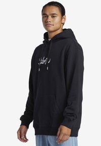 Sudadera con capucha negra, con bolsillo frontal, cordones con puntas metálicas y gráfico de logo blanco en el pecho, que presenta mangas largas y puños de canalé.
