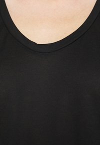 Černé bavlněné tričko s klasickým kulatým výstřihem. Hladká textura s mírným leskem, bez viditelných vzorů nebo kovových prvků.