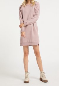 Vestido de sudadera rosa claro, hecho de un tejido suave, con mangas largas, puños acanalados, aberturas laterales y un ajuste relajado. Combinado con botas color crema.