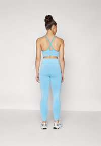 Hellblaues sportliches Crop-Top mit Racerback-Design und Schlüsselzugdetail, kombiniert mit passender, hochtaillierter Leggings, glatte Stoffstruktur.