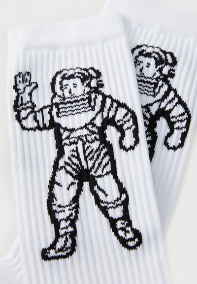 White socks with a ribbed texture, featuring a black astronaut design. The astronaut has a waved hand and detailed suit accents.
