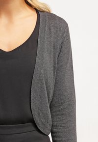 Dunkelgrauer Cardigan mit offenem Vorderteil, leichtem Strickstoff und langen Ärmeln, getragen über einem schwarzen Oberteil.