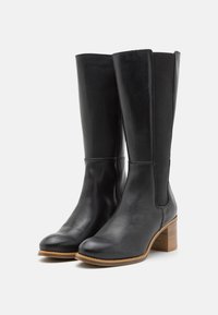 Botas de cuero negro hasta la rodilla con puntera redonda, tacón cuadrado y paneles laterales elásticos para facilitar el uso y la comodidad.
