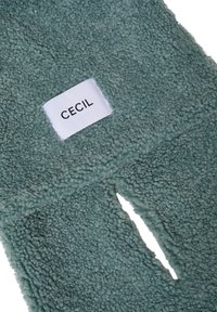 Fleece tørklæde i dæmpet teal med en blød, tekstureret overflade. Har en udskæring og et hvidt etikette med "CECIIL" i fed sort skrift.