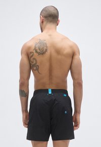 Μαύρο μαγιό βερμούδα με ελαστική μέση, μπλε λεπτομέρειες και τατουάζ φιδιού στο πίσω μέρος. Ομαλή υφή, μήκος πάνω από το μέσο του μηρού.