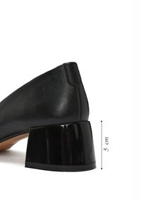 Scarpa in pelle nera con punta affusolata, dotata di un tacco a blocco lucido di 5 cm e superficie liscia. La vista laterale mostra linee pulite.