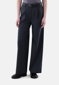 Weite Hosen aus dunkelgrauem Stoff mit feiner Textur. Ausgestattet mit einem schwarzen Gürtel und mit vorderen Falten für zusätzlichen Detailreichtum gestaltet.