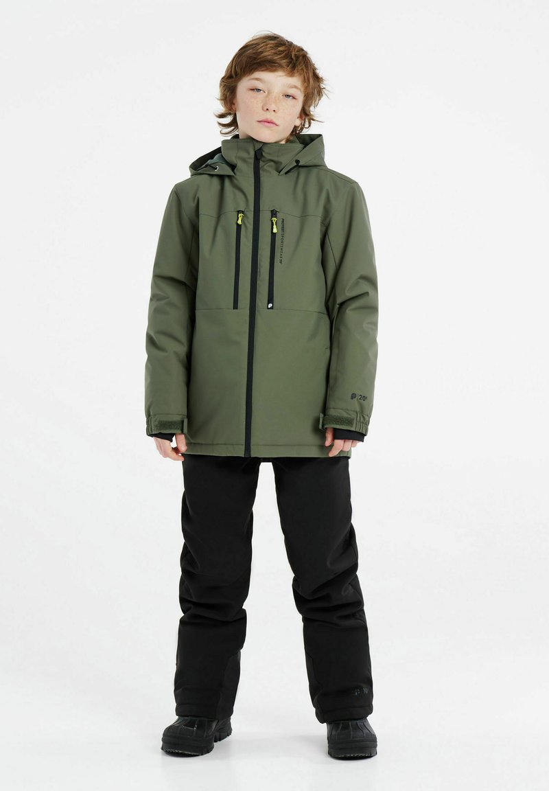 Veste imperméable verte avec fermeture éclair à l'avant et deux poches, associée à un pantalon noir et des bottes de neige, dotée d'une capuche et de poignets réglables.