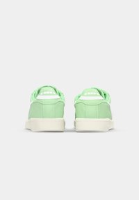 Sneaker verdi con tomaia in tessuto testurizzato, dettagli bianchi e suola in gomma. Presentano un collare imbottito e un logo sul tallone.