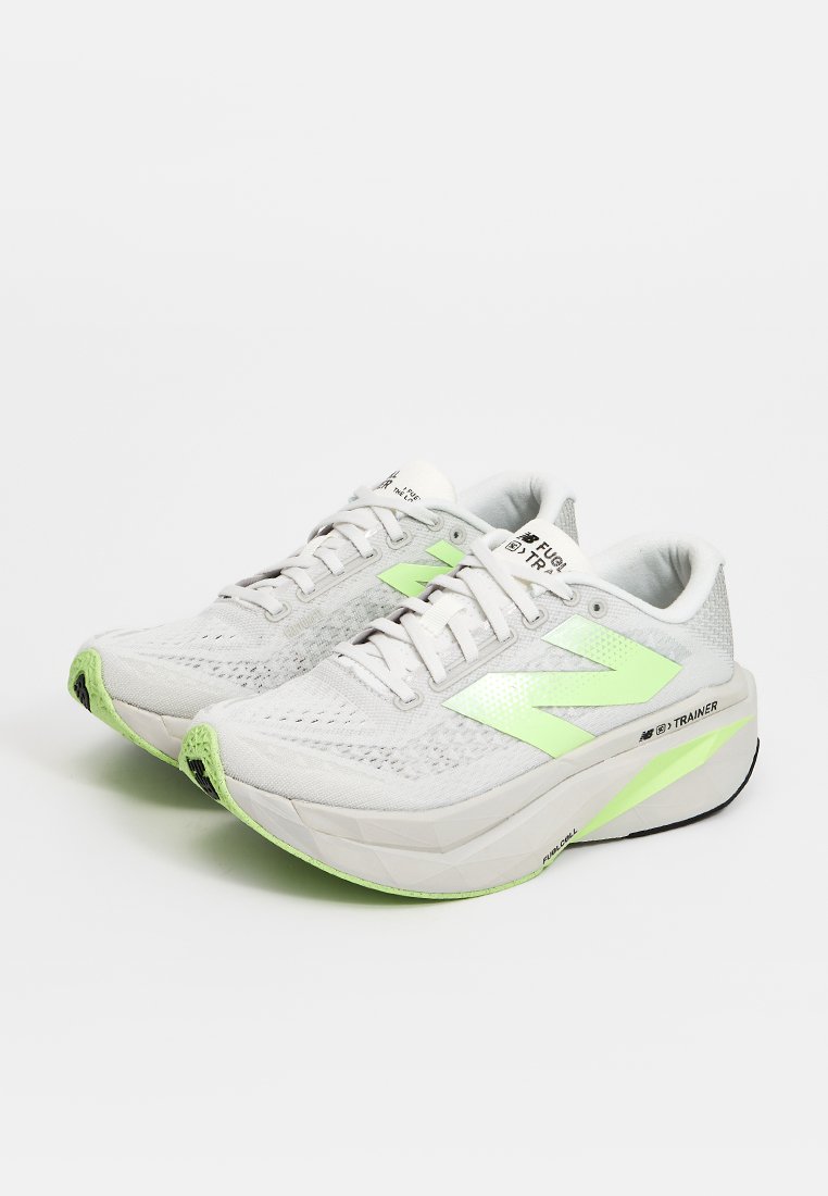Paire de chaussures de course blanches et vert clair avec des semelles épaisses et des lacets, légèrement inclinées vers la gauche sur fond blanc.