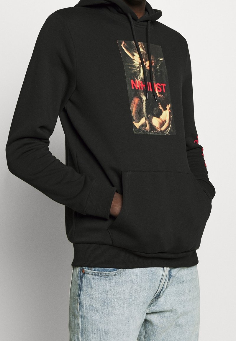 Sudadera negra de algodón con un gráfico en el frente que presenta una pintura y la palabra "NIHILIST" en rojo, con un bolsillo tipo canguro y puños acanalados.