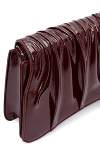 Borsa in pelle verniciata bordeaux con un design ondulato, caratterizzata da una texture lucida, cuciture precise e una forma strutturata.