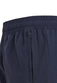 Bermudas ligeras de color navy con cinturilla elástica, que cuentan con un bolsillo lateral con cremallera, hechas de una tela suave y transpirable con un sutil brillo.