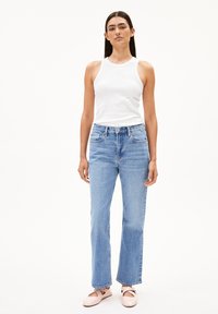 Un top à fines rayures blanc associé à un jean droit taille haute bleu clair et des ballerines rose pâle. Tenue simple et décontractée.