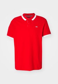 Camisa polo de algodón roja con un cuello y puños a rayas blancas, con un pequeño logo en el lado izquierdo del pecho. Corte clásico, mangas cortas.