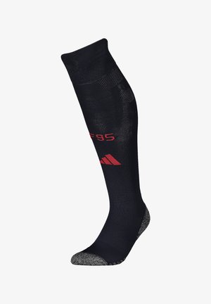 Chaussette noire montante en tissu texturé, avec un embout renforcé en gris chiné et un détail de marque rouge. Offre un ajustement confortable et rembourré.