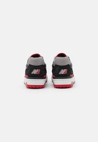 Scarpe da ginnastica nere e grigie con suola rossa e dettagli in rosso, upper testurizzato e logo bianco prominente sul tallone.