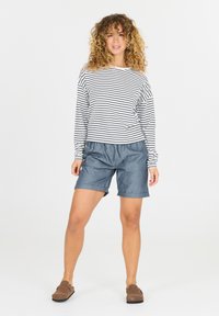 Gestreept overhemd met lange mouwen in zwart en wit, gecombineerd met blauwe denim shorts. Casual ontwerp met een royale pasvorm, met opgerolde mouwen.
