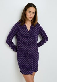 Nottura viola con un motivo fogliare, maniche lunghe, frontale con bottoni e una vestibilità ampia con tasche laterali.