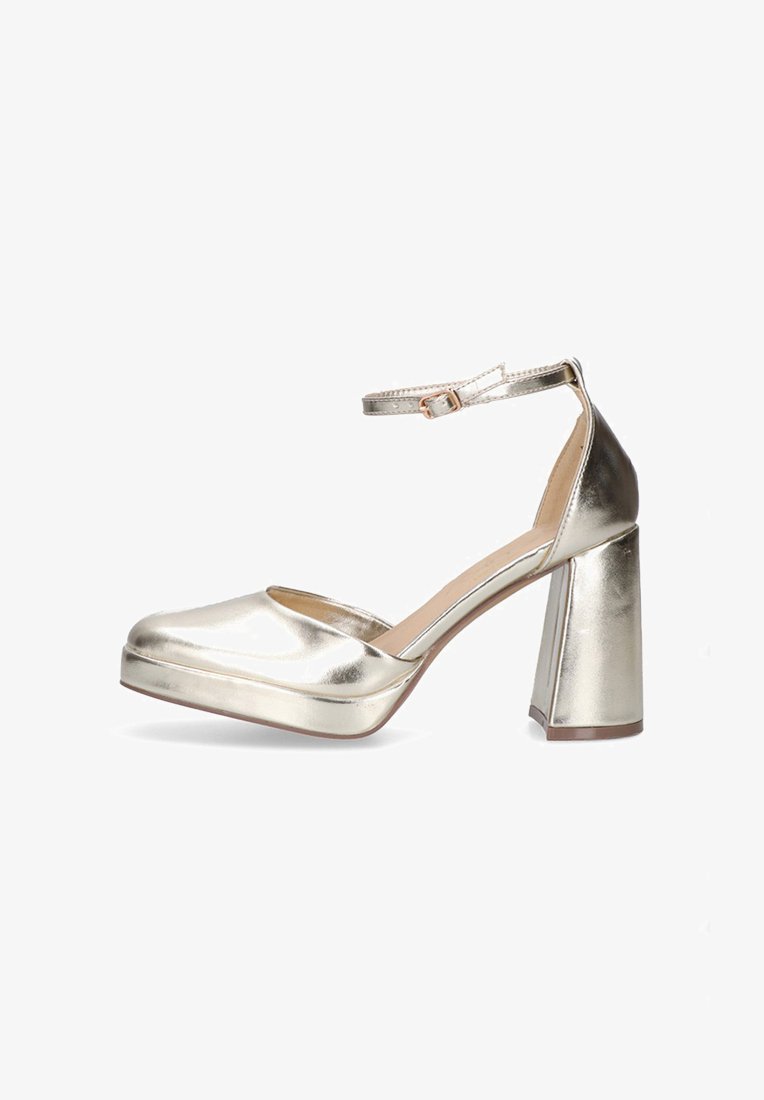 Zapatos de tacón de plataforma metálicos dorados con punta cuadrada, correa al tobillo y tacón de bloque grueso. Textura suave con un acabado brillante.